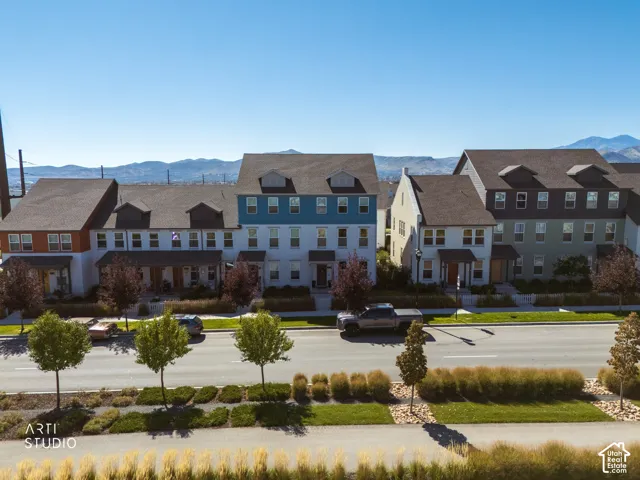Row of multi-story townhomes with dormer windows, individual front porches, and varied exterior siding colors