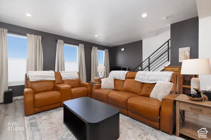 Recessed ceiling lighting, wood-finish flooring, multiple windows with blinds, a modern black metal staircase, and dark accent walls