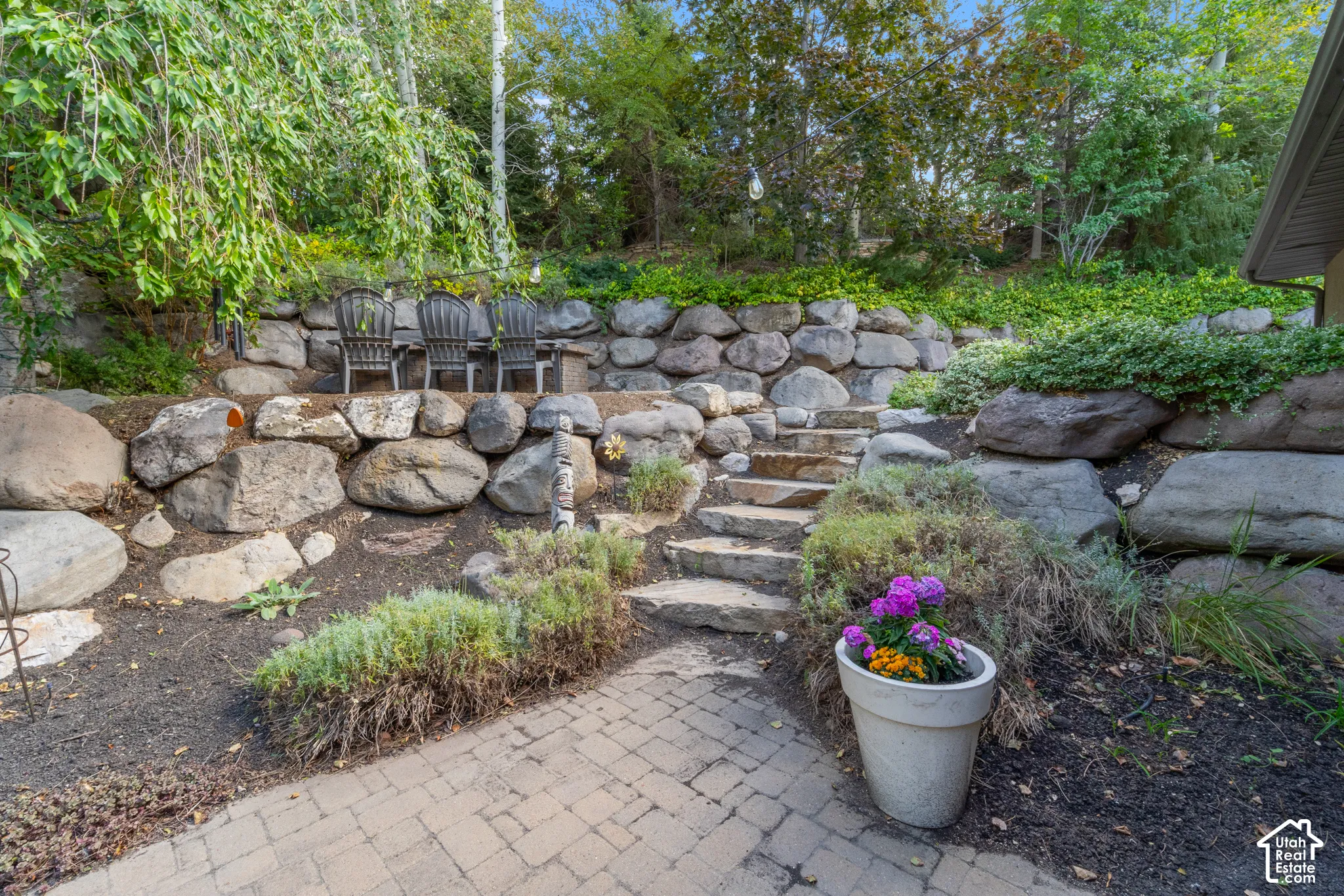 Paver patio with stone steps leading to a tiered seating area, with fire table.