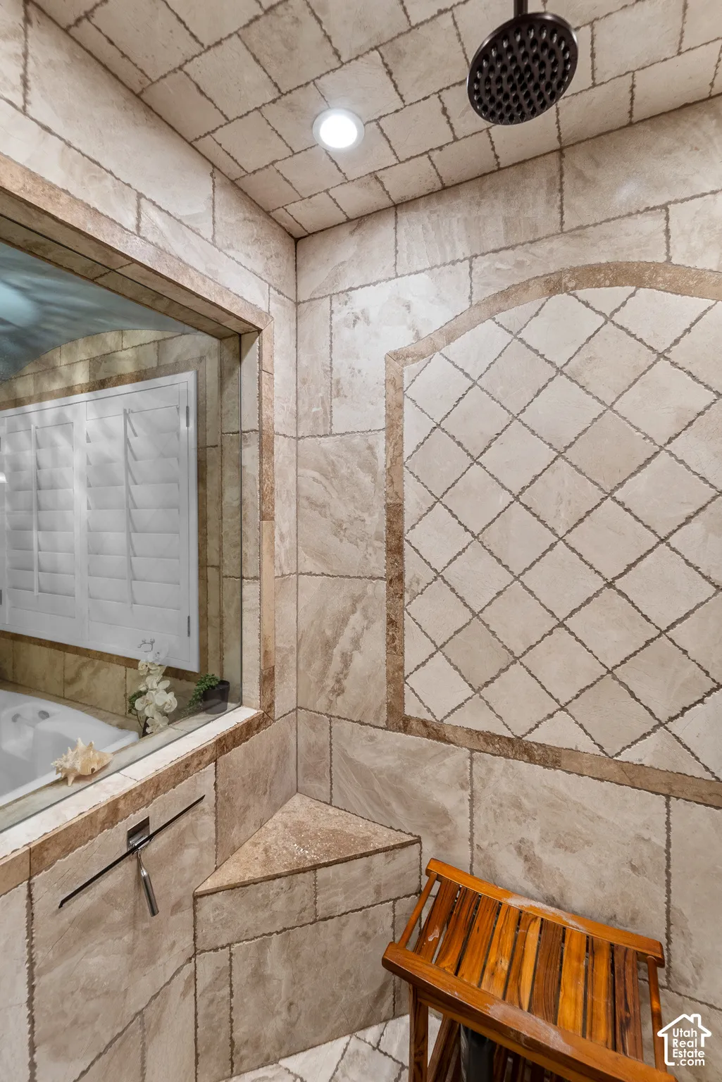 The Spa-inspired bathroom continues into the generously sized shower with it's custom stone tile walls and ceiling, frameless glass shower enclosure, built in shelves and overhead rainfall showerhead.