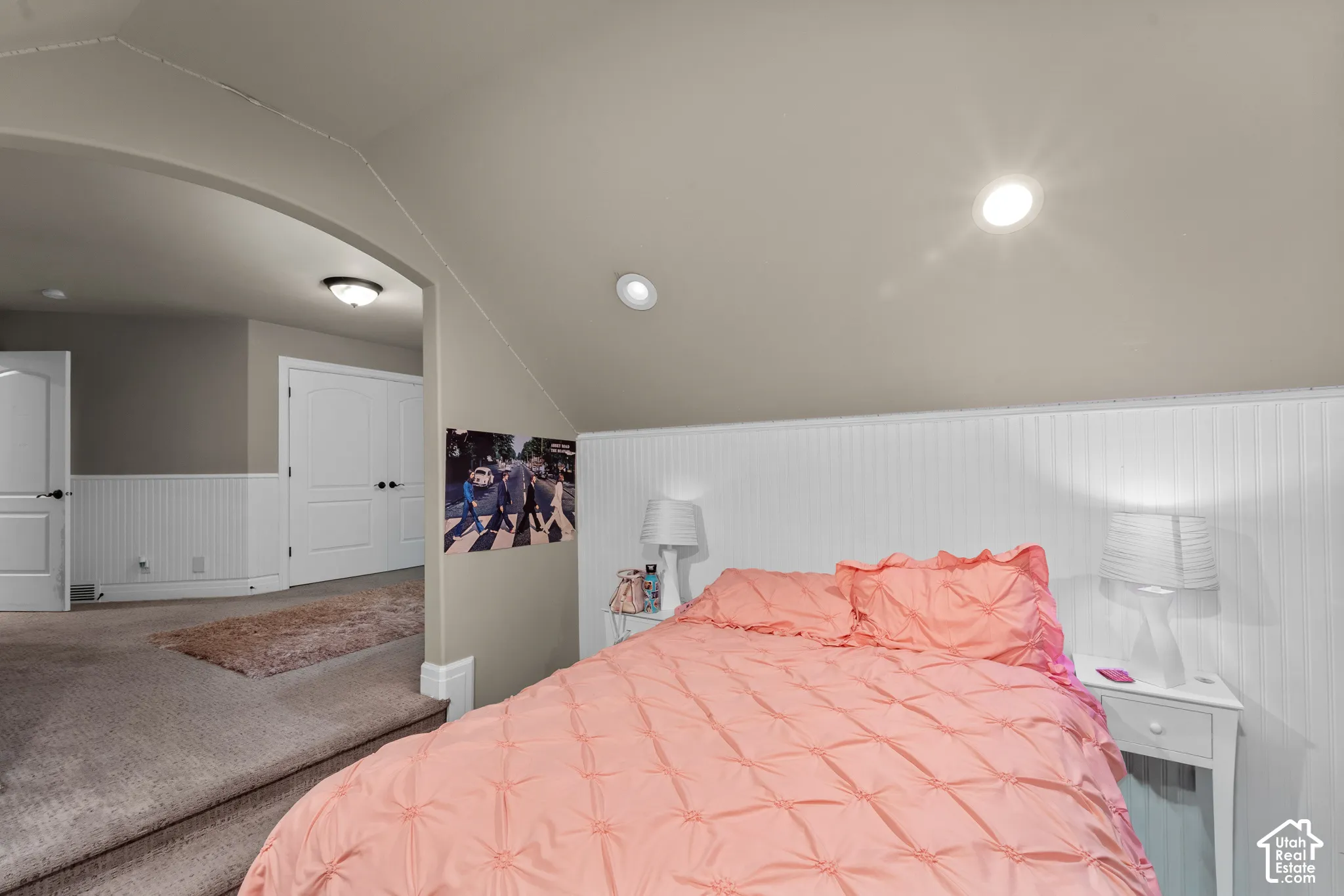 Sloped ceilings with recessed lighting, beadboard wainscoting, and an arched doorway