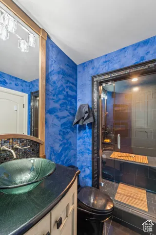 Vibrant blue wall finishes, a custom green vessel sink with a beautiful wood vanity is just the beginning to this bathroom.  The expansive walk-in shower is a steam shower with beautiful tile.