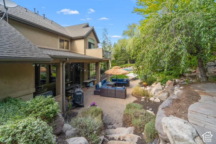 Expansive backyard retreat featuring a multi-level paver patio with integrated seating area, fire pit and a great view of the waterfall. On the right side of this picture you can see the level with the fire table in the next picture.