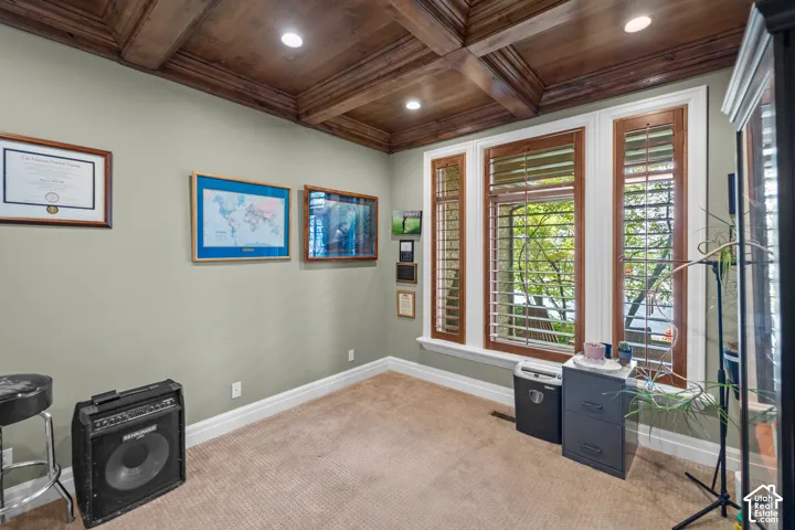 A coffered wood ceiling, recessed lighting, wood-framed windows, plantation shutters, and large windows make this a perfect space to work from home.