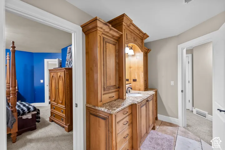 The custom wood vanity with and integrated sink make getting ready for your day a treat. There is plenty of storage and beautiful tile floors. From this view you can see into the hall and the second bedroom.