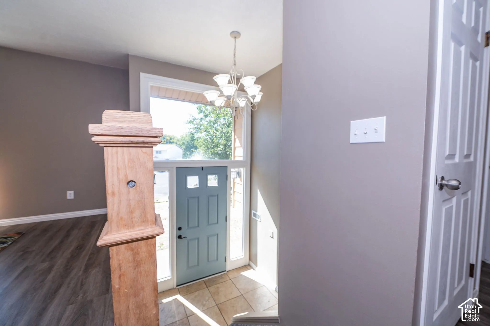 Tiled entry with a chandelier, wood-finish flooring, and a paneled door