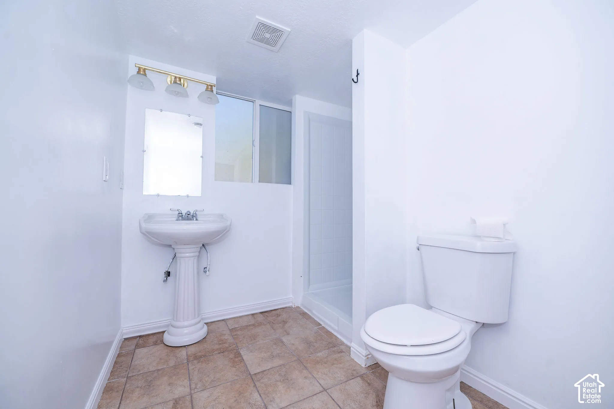 Pedestal sink with chrome fixtures, tiled flooring, white wall paint, toilet, and shower enclosure