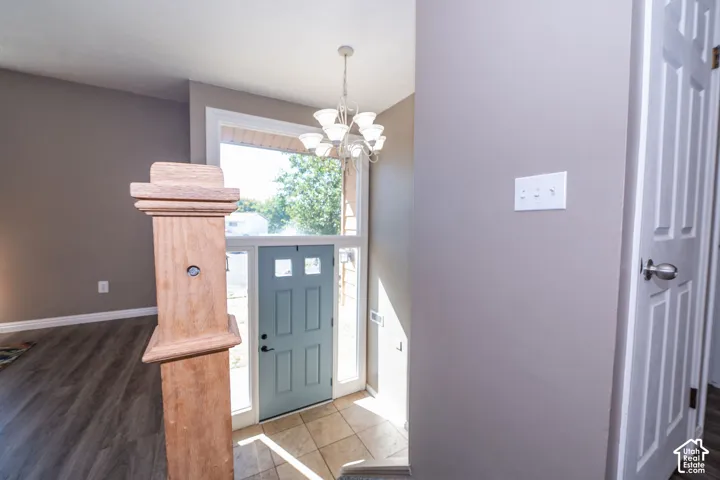 Tiled entry with a chandelier, wood-finish flooring, and a paneled door