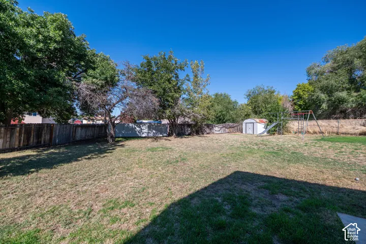Expansive grassy yard with mature trees and a privacy fence