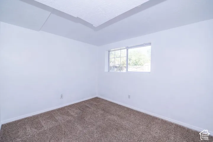 Neutral tone carpeting, white painted walls, and a window providing natural light