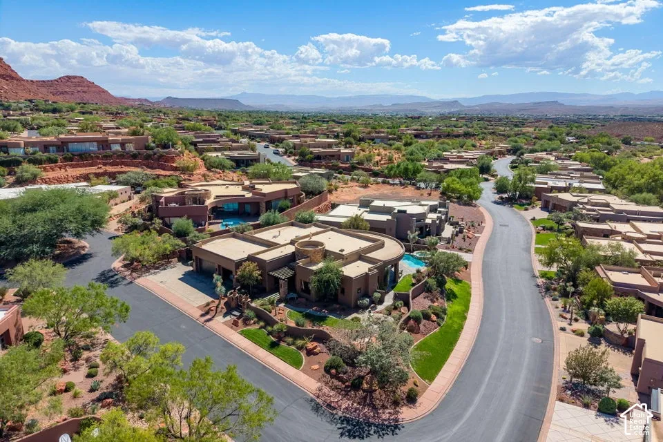 Desert landscape with a paved road, multiple residential structures, and distant mountains