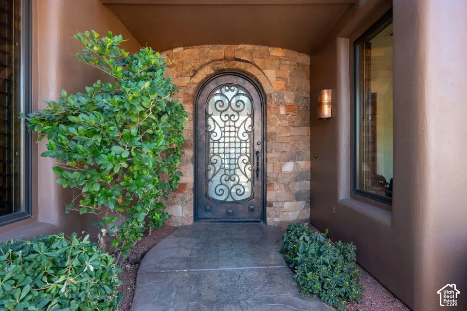 Arched entryway featuring an ornate wrought iron and glass door, stone surround, and stucco exterior