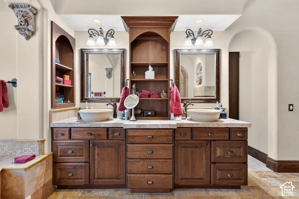 Dual vessel sinks, dark wood-finish cabinetry, built-in shelving, and complementary framed mirrors