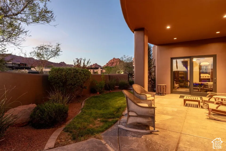 Patio with overhead lighting, sliding glass doors, concrete flooring, and surrounding landscaping