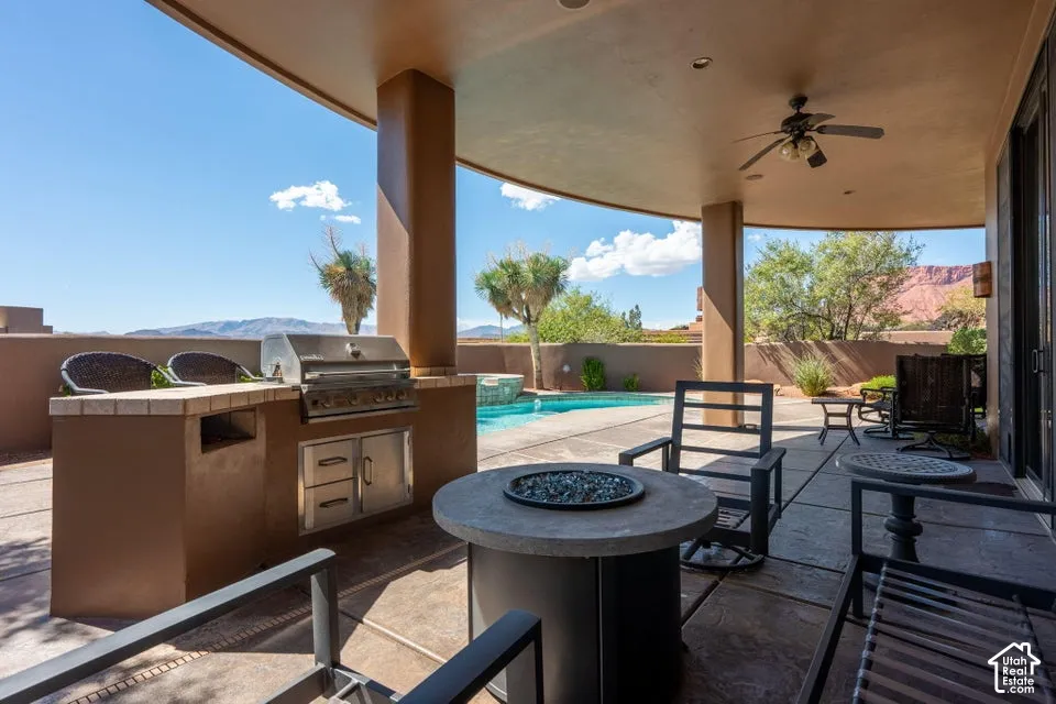 Covered outdoor patio with a built-in grill, integrated cabinetry, and an outdoor ceiling fan