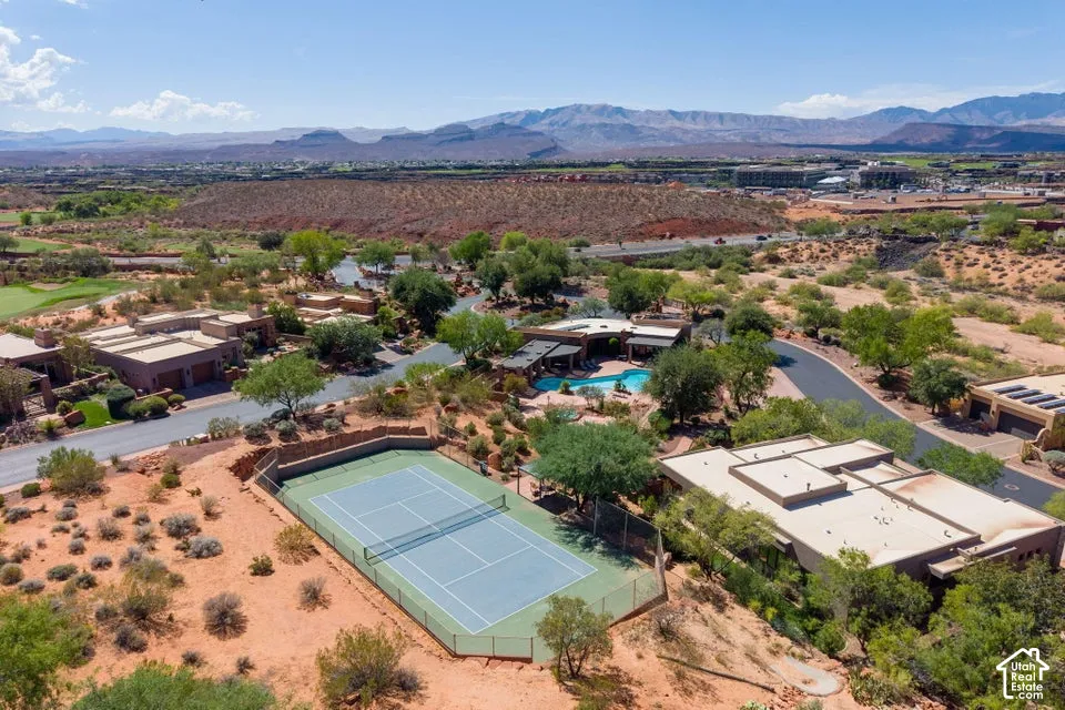 Aerial perspective showcasing arid landscape, a tennis court, a residential street, and distant mountains