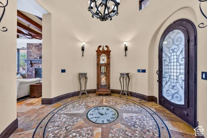 Arched entry door with decorative ironwork, custom tile mosaic flooring, and vaulted ceiling with exposed wood beams