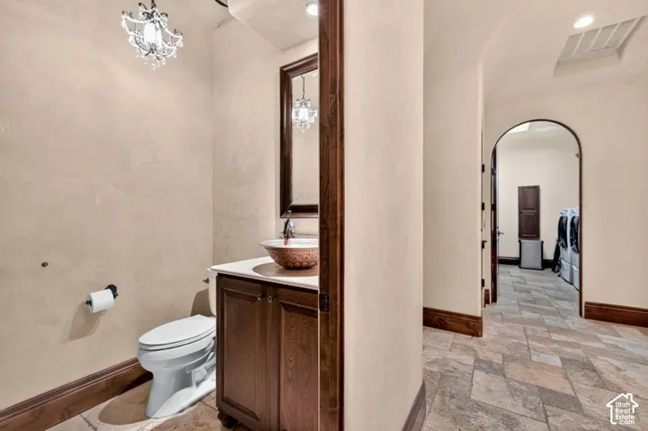Powder room featuring a decorative vessel sink, dark wood-finish vanity, and an ornate chandelier