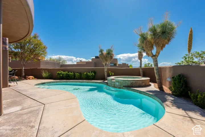 Curved swimming pool with integrated spa, surrounded by concrete decking and mature desert landscaping