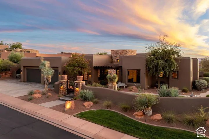 Desert Contemporary residence featuring a stucco exterior, integrated two-car garage, and a wrought iron gate entry