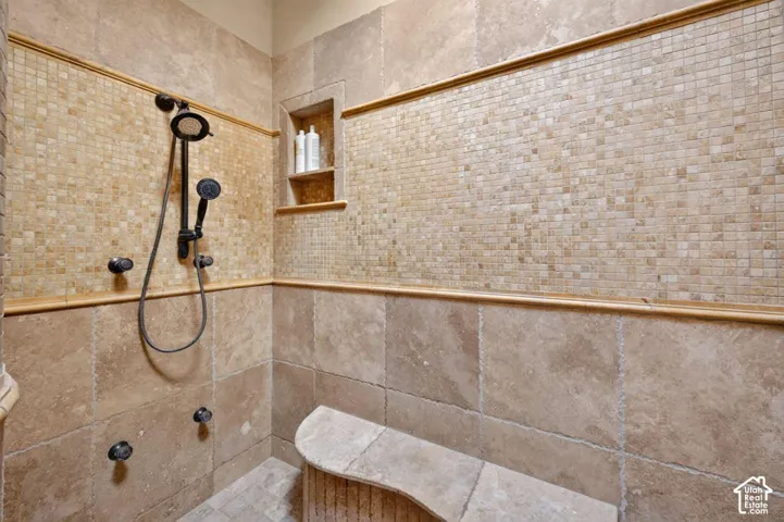 Tile shower with mosaic accent, built-in niche, and curved bench