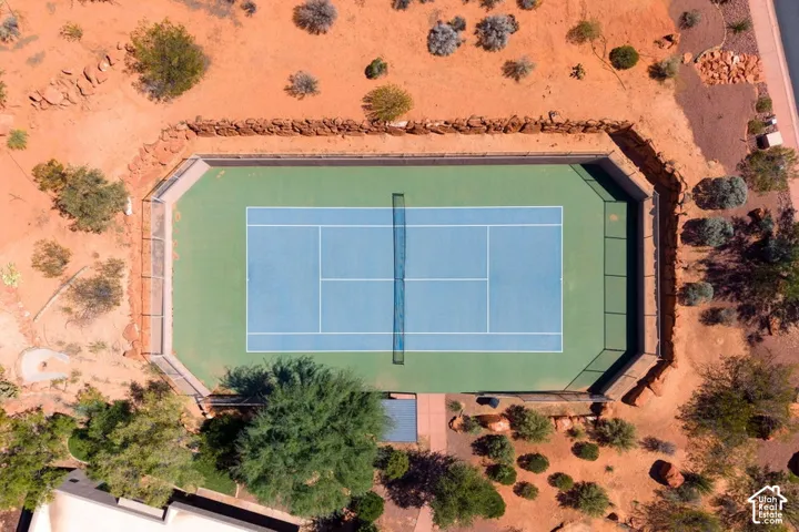 Full-size tennis court featuring a blue playing surface, green perimeter, and a dark net