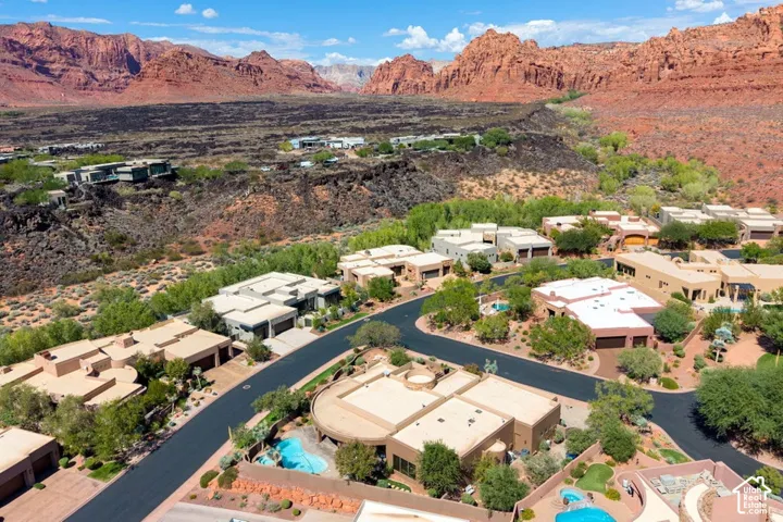 Aerial perspective showcasing a residential community with desert landscaping, private swimming pools, and paved roadways, set against a backdrop of natural rock formations