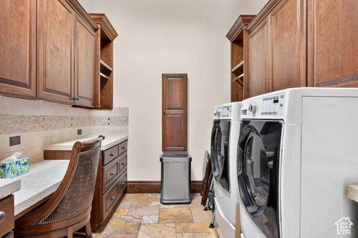 Wood-finish cabinetry, stone tile flooring, built-in desk, and light-toned countertops