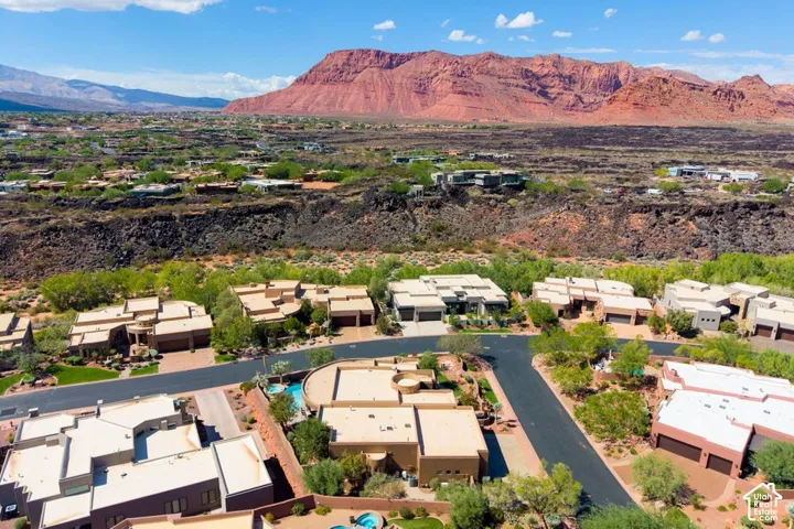 Aerial perspective showcasing a residential community with contemporary architecture, multiple properties featuring integrated garages, and a prominent red rock mountain range in the background