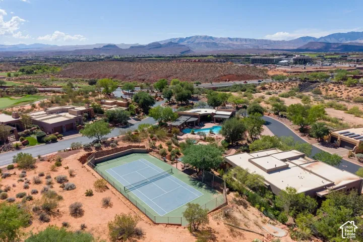 Aerial perspective showcasing arid landscape, a tennis court, a residential street, and distant mountains