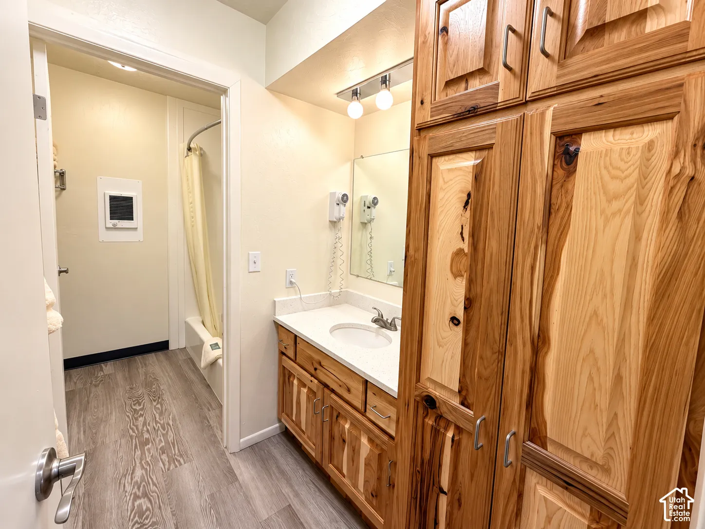 Wood-finish flooring with a white vanity featuring a single basin sink and a stone-look countertop