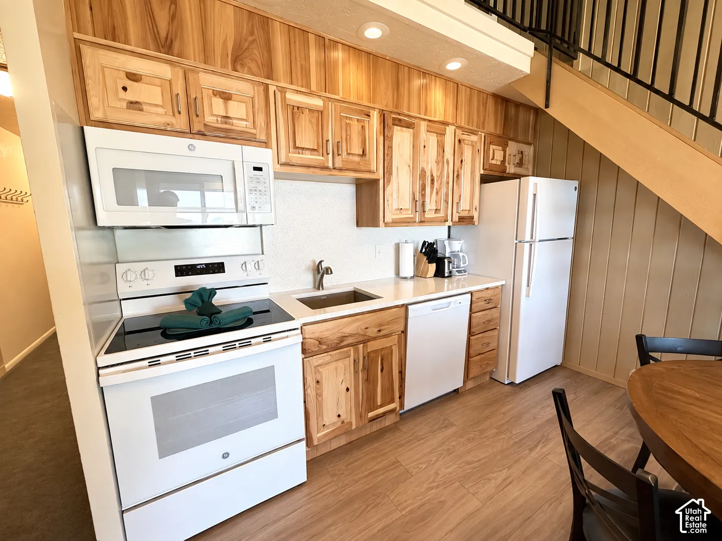 Kitchen featuring wood-finish cabinetry, white appliances, and light-colored countertops