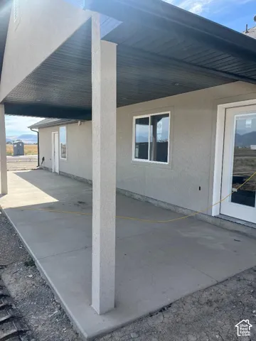 Exterior featuring a covered concrete patio, stucco siding, and white-framed windows