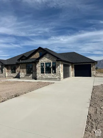 Stone and wood-finish exterior with a dark shingle roof and a paved driveway