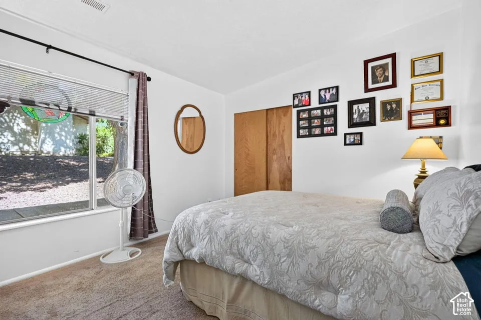 Carpeted flooring, built-in closet with wood-finish doors, and a window with blinds