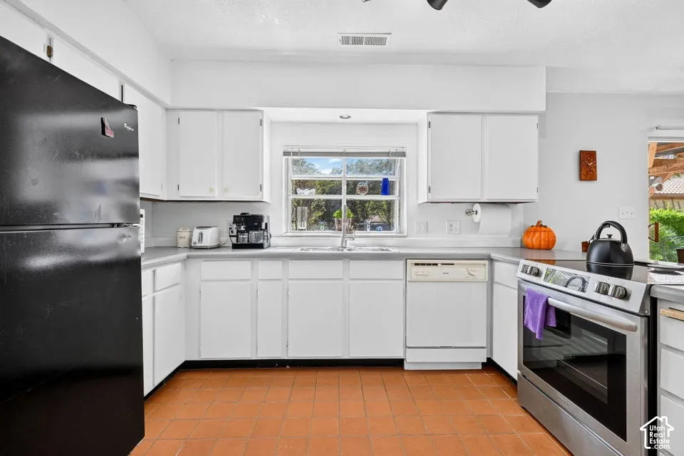Kitchen featuring white cabinetry, a window over the sink, stainless steel range, and tile flooring