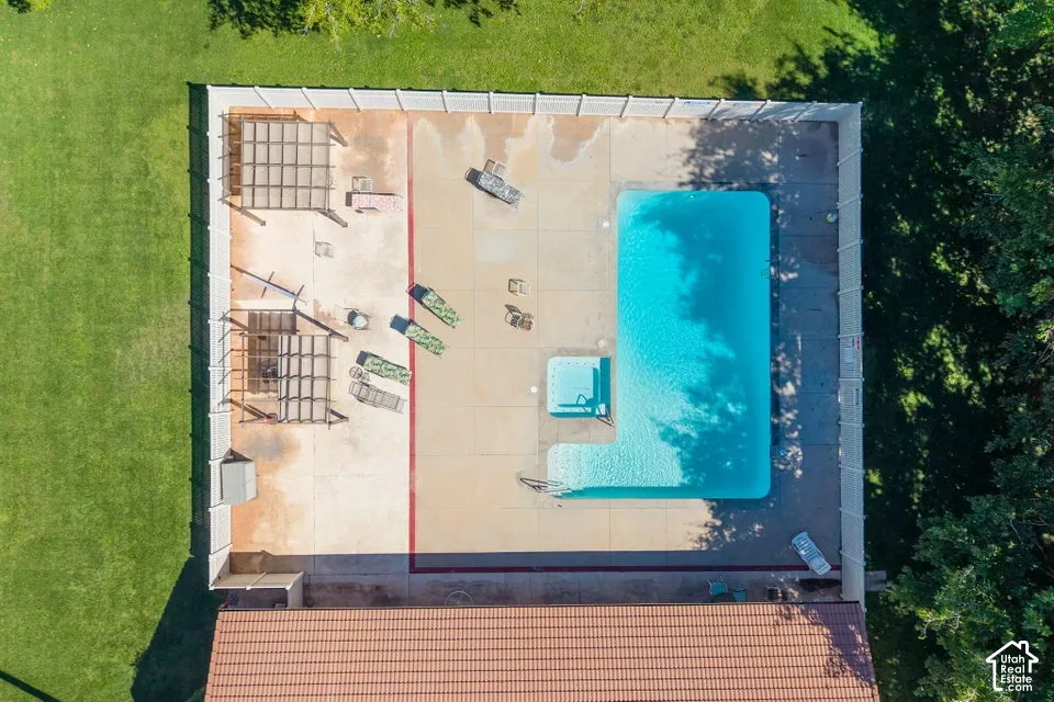 Expansive concrete patio with an L-shaped swimming pool and an integrated spa
