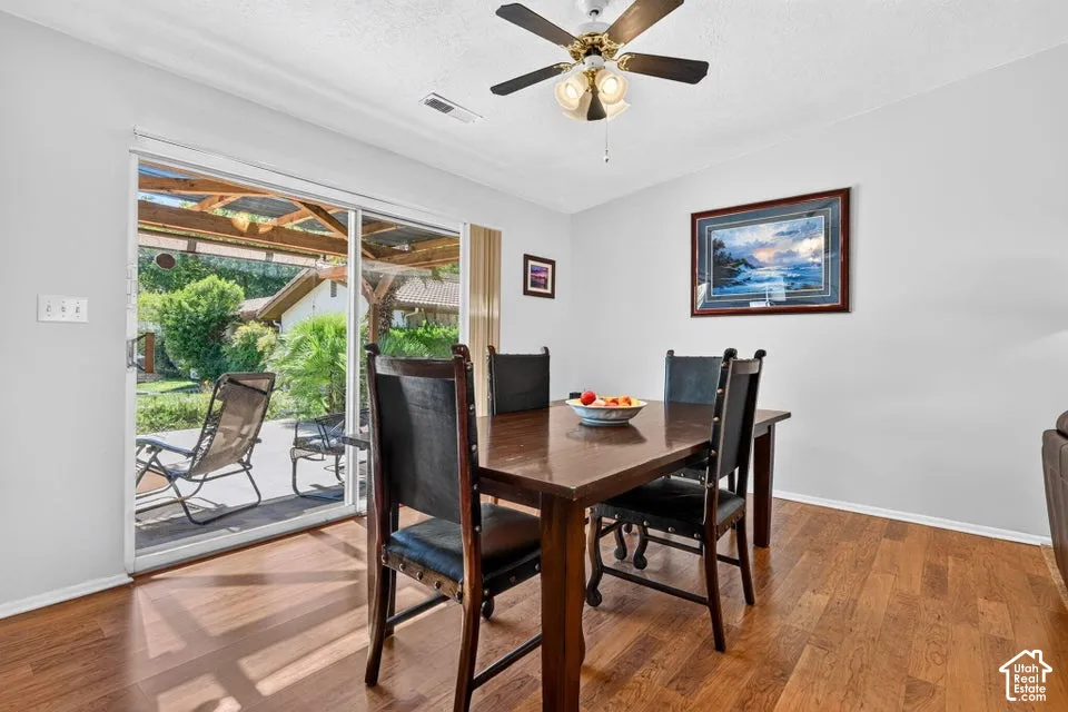Wood-finish flooring with a ceiling fan light fixture and sliding glass door access to a covered patio