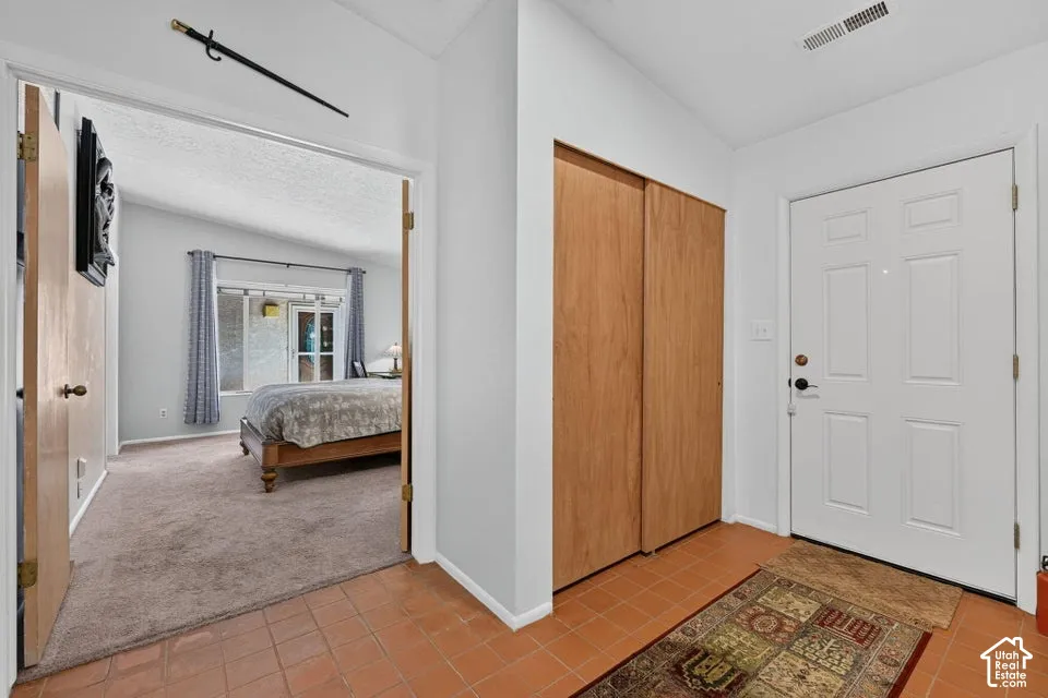 Entryway with terra cotta floor tiles and light wood-finish bi-fold closet doors