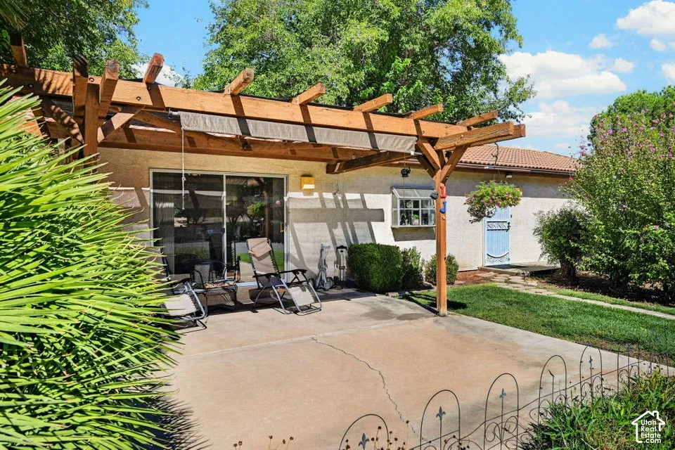 Outdoor living space featuring a wood pergola with shade fabric, concrete patio, and sliding glass doors