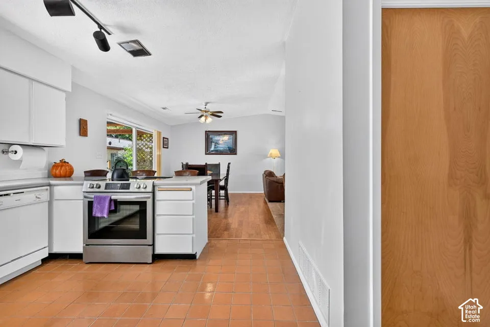 Kitchen featuring tile flooring, white cabinetry, stainless steel range, and track lighting