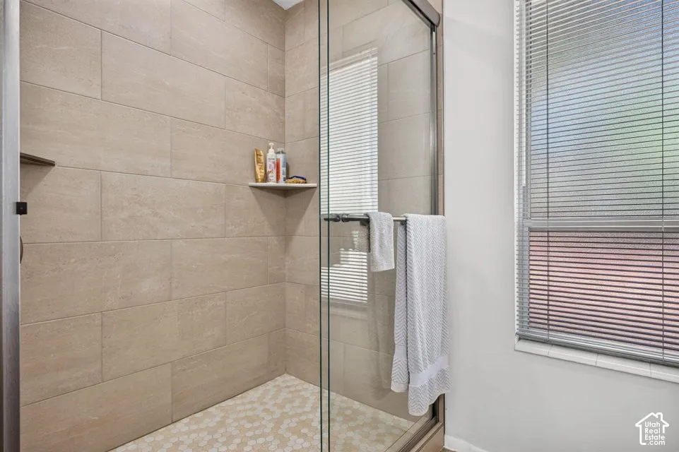 Glass-enclosed shower featuring large format tile walls and a hexagonal tile floor