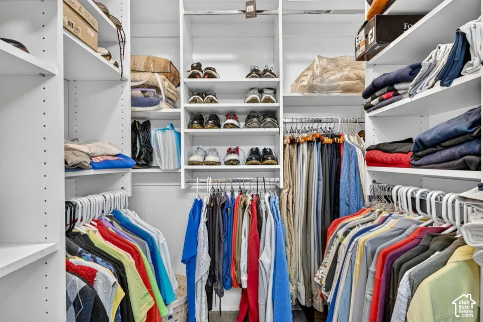 Custom closet system with white shelving, multiple hanging rods, and integrated shoe racks