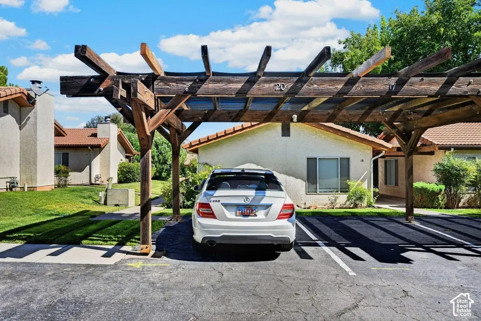Dedicated parking space featuring a wood pergola, asphalt paving, and painted parking lines