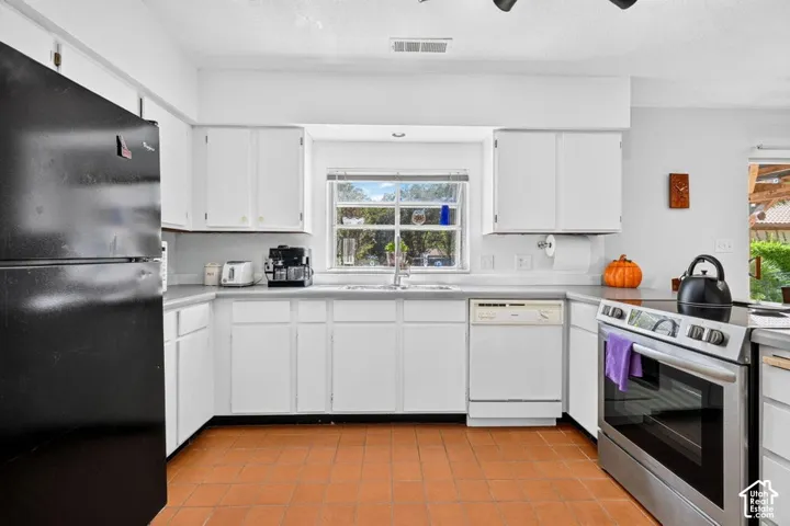 Kitchen featuring white cabinetry, a window over the sink, stainless steel range, and tile flooring