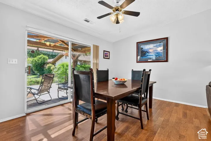 Wood-finish flooring with a ceiling fan light fixture and sliding glass door access to a covered patio