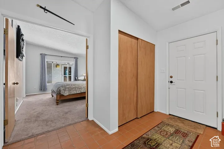 Entryway with terra cotta floor tiles and light wood-finish bi-fold closet doors