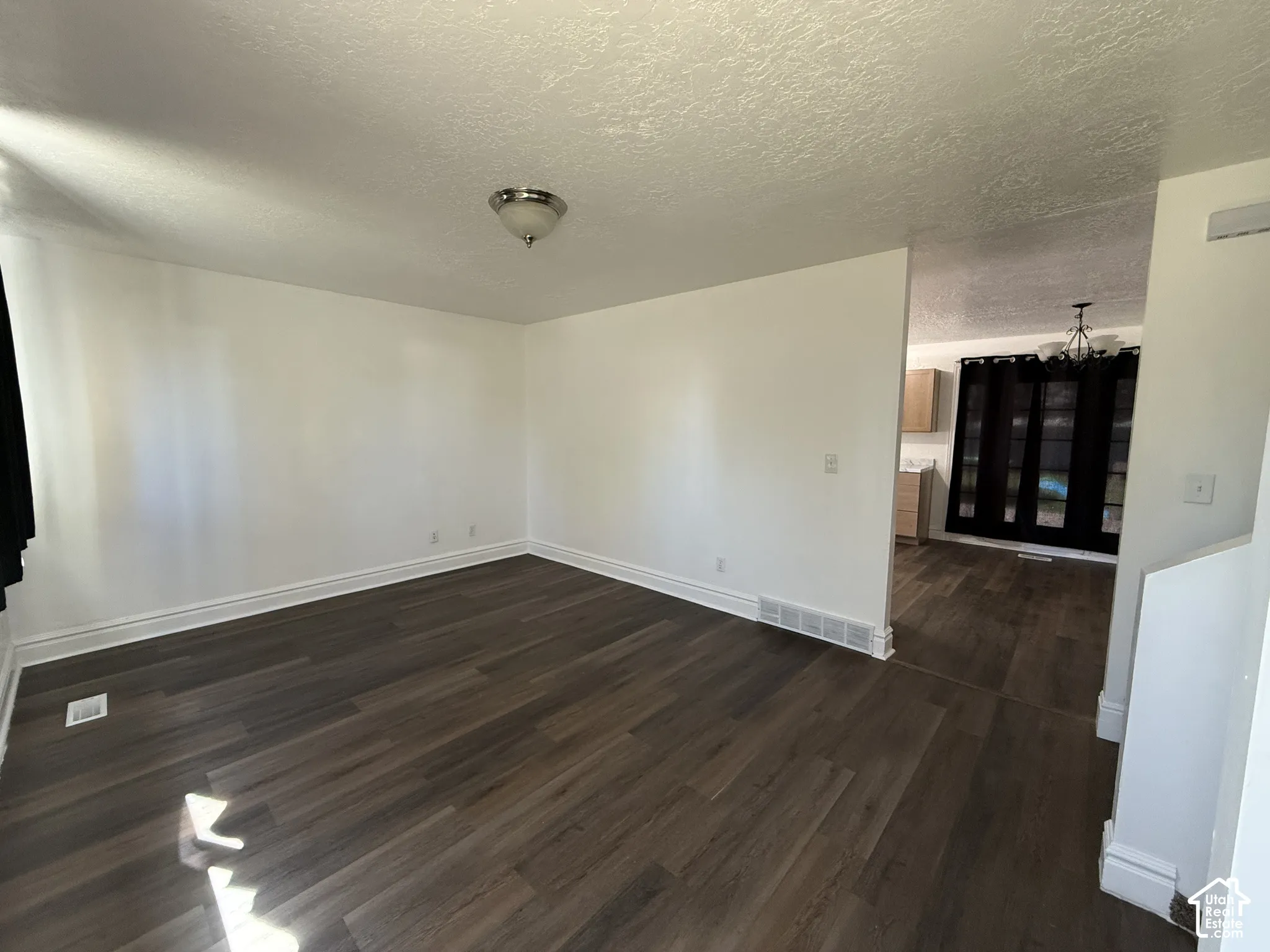 Wood-finish flooring throughout, bright white walls, and a semi-flush mount ceiling light fixture