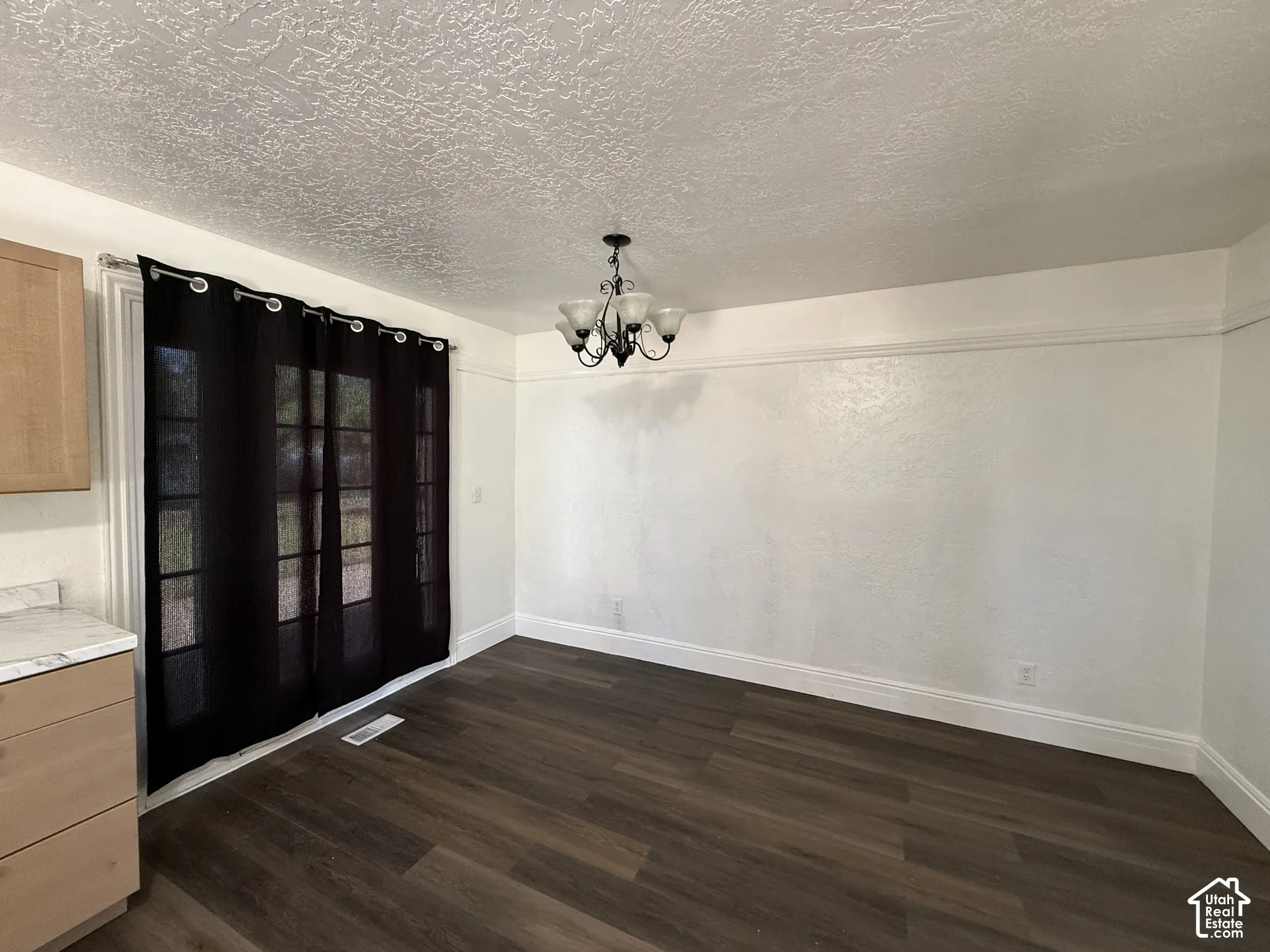 Wood-finish flooring with white trim, a decorative ceiling, and a multi-light chandelier
