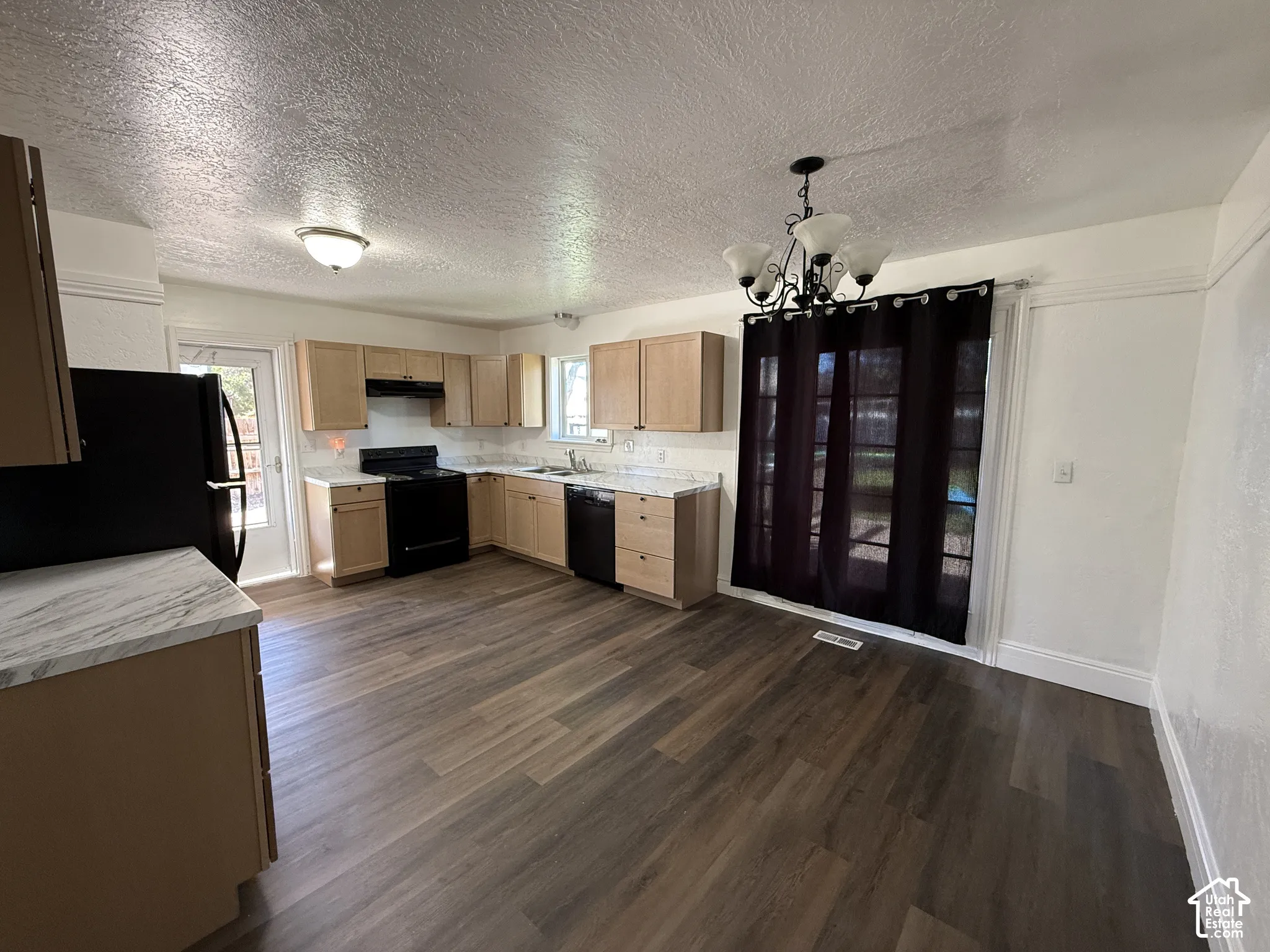 Kitchen featuring wood-finish flooring, light wood cabinetry, black appliances, and a marble-look countertop